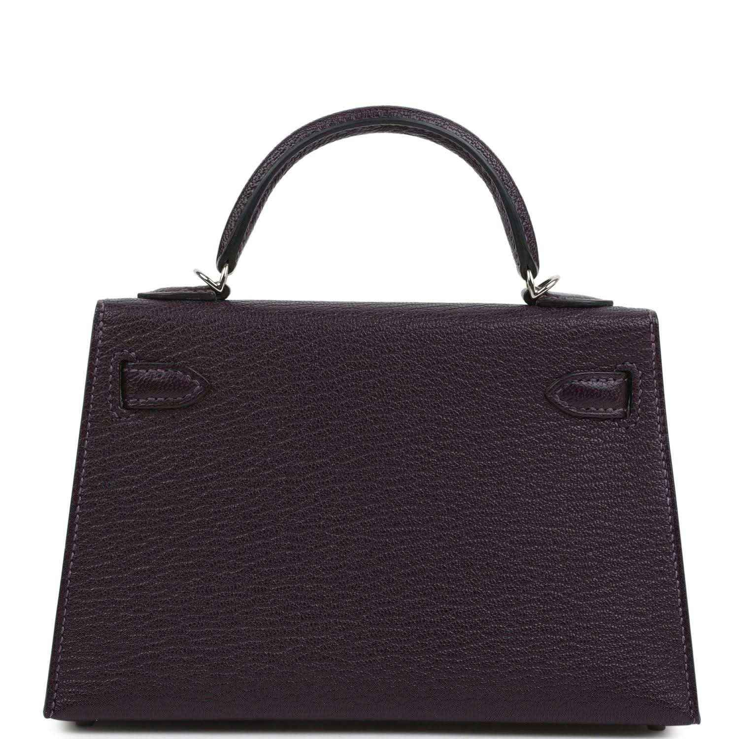 Purple leather handbag with top handle and back panel, embossed corner details.