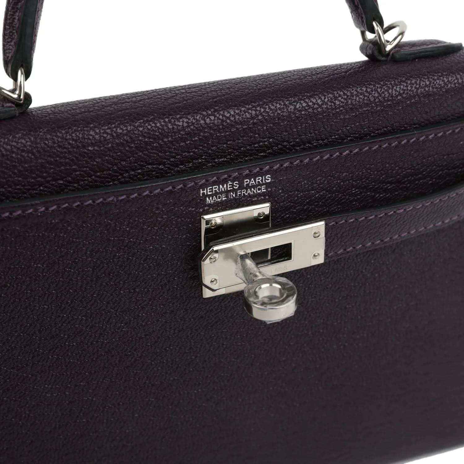 Metal clasp on purple leather handbag with engraved 'HERMES PARIS' and lock.
