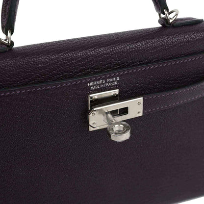 Metal clasp on purple leather handbag with engraved 'HERMES PARIS' and lock.