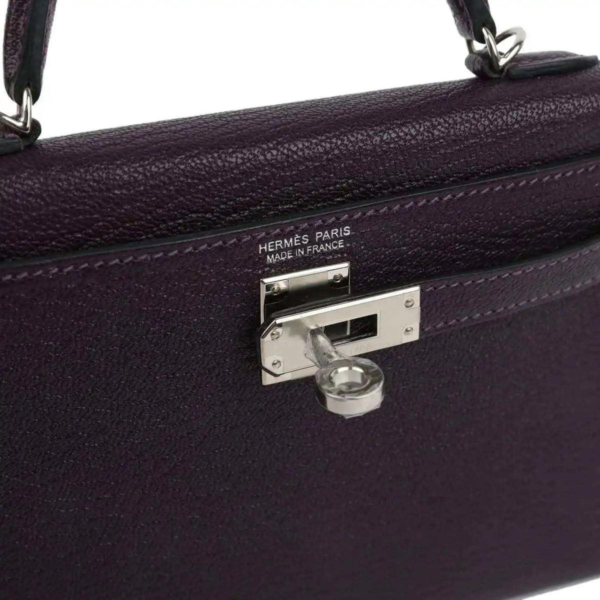 Metal clasp on purple leather handbag with engraved 'HERMES PARIS' and lock.