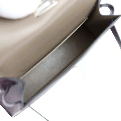 Beige interior lining of purple leather handbag with folded edge seam.