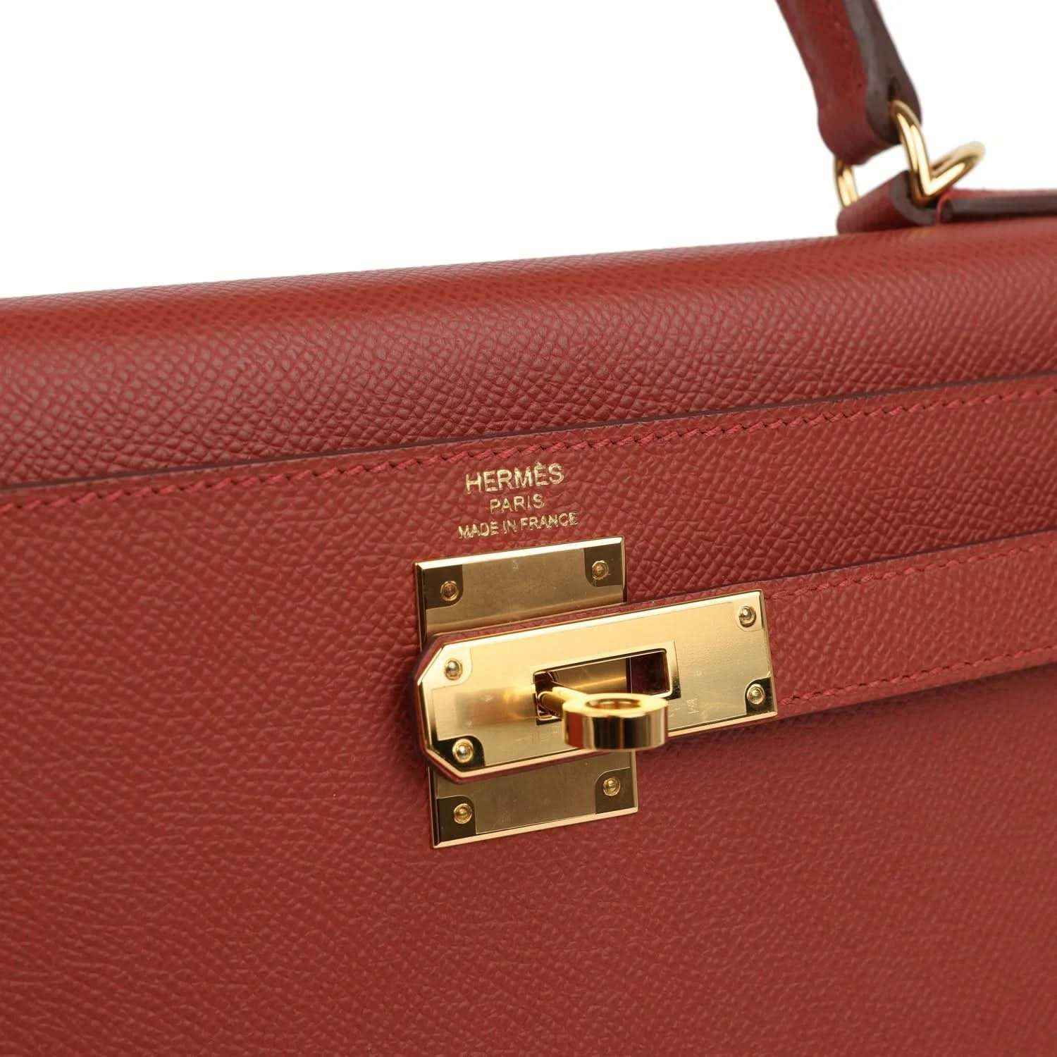 Gold clasp on red Kelly handbag with Hermes engraving and textured leather