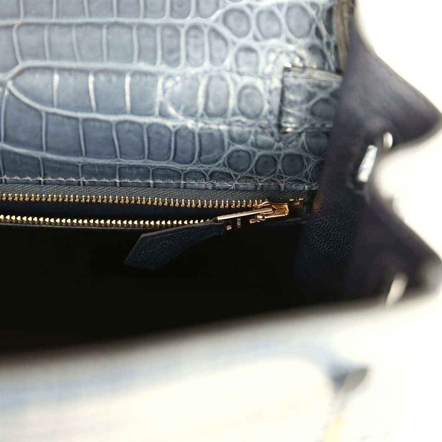 Hermès Kelly Retourne 28 bag close-up of zipped pocket, gold zipper, dark blue croc