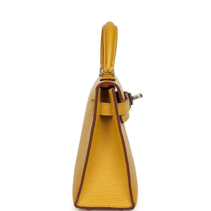 Yellow leather handbag side view with top handle and strap hardware, silver-tone details