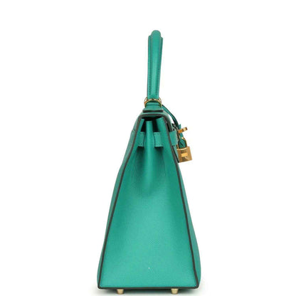 Green leather Kelly-style handbag with top handle, front facing, and gold feet on base.