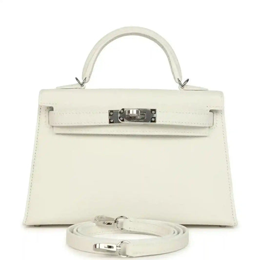 White mini Kelly-style handbag with top handle, front flap, metal clasp, and shoulder strap