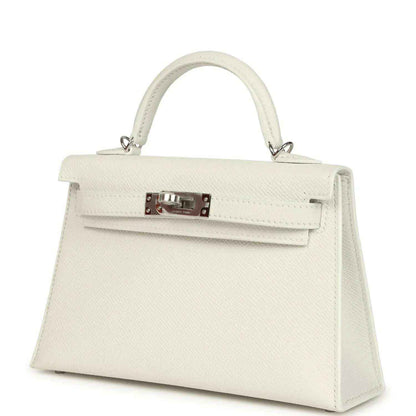 White mini Kelly-style handbag angled view with front flap and metal clasp