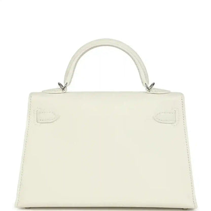 White mini Kelly-style handbag back view with top handles and stitched panel details