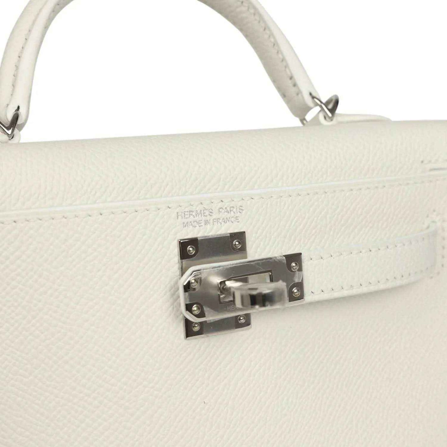 White mini Kelly-style handbag close-up of front clasp hardware on the flap