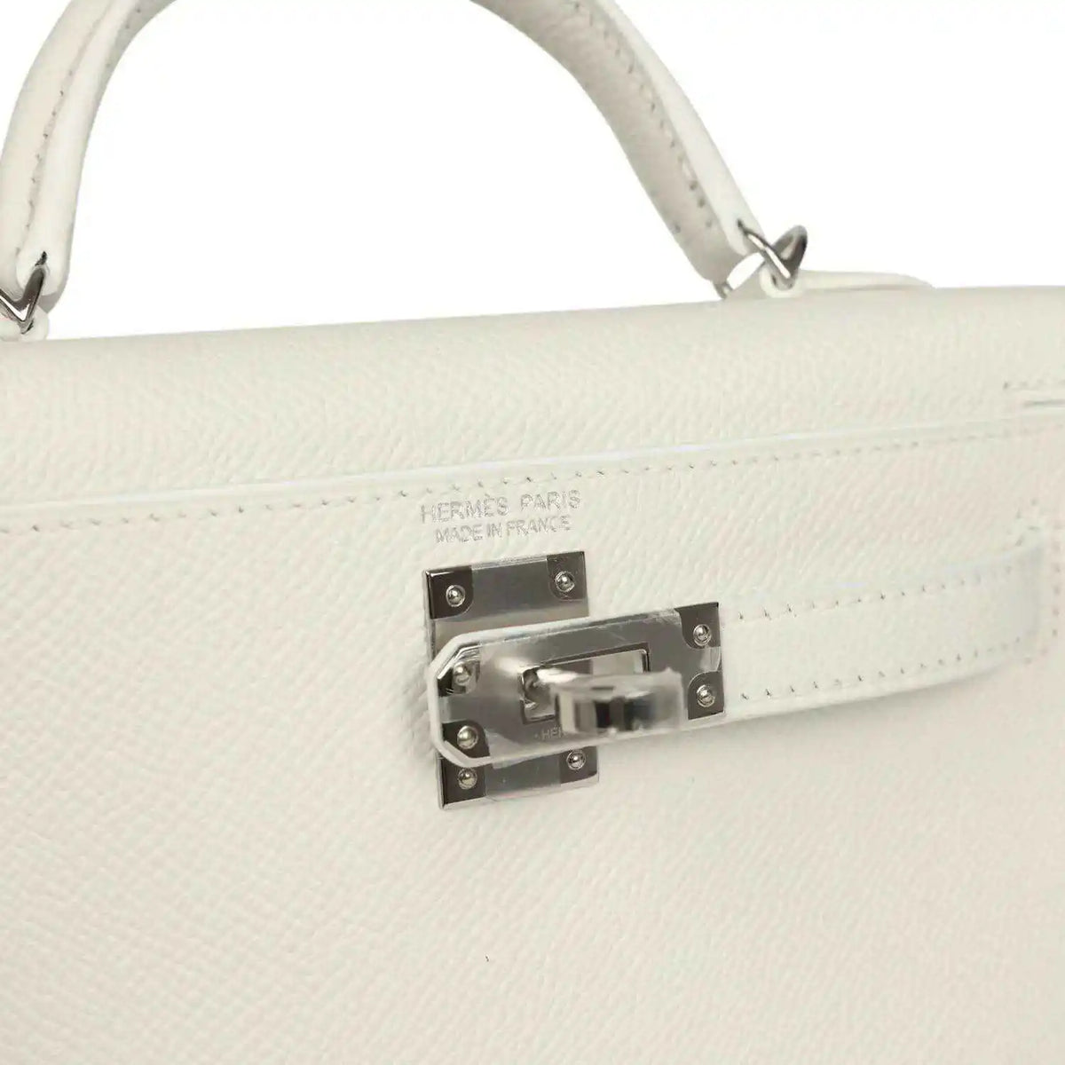 White mini Kelly-style handbag close-up of front clasp hardware on the flap