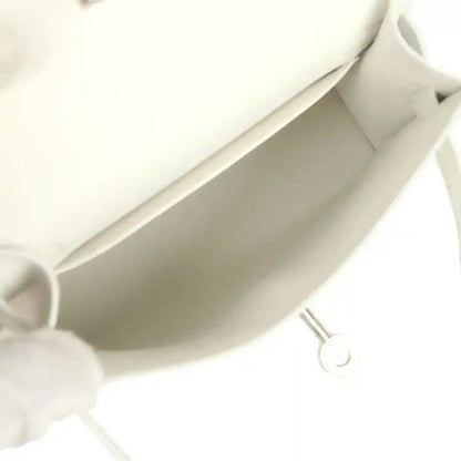 White mini Kelly-style handbag interior view with lining and side pocket wall