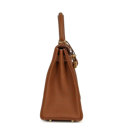 Tan brown leather handbag side view with structured sides and gold hardware feet