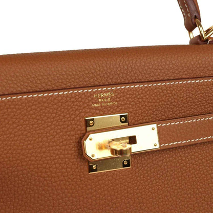 Hermes Togo leather handbag lock, gold-tone hardware, white contrast stitching