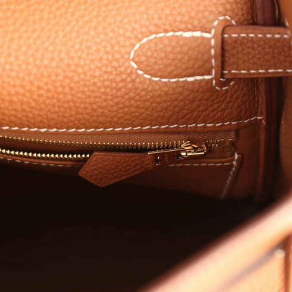 Tan leather handbag pocket with zip pull, gold-tone zipper, and stitched panel