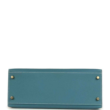 Blue leather handbag back panel with four corner studs and visible edge stitching.
