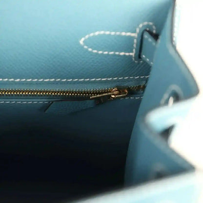 Blue leather handbag interior with gold zipper and stitched panel near the slip pocket.