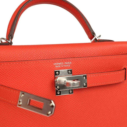 Red leather Kelly bag close-up of front lock plate and stitched flap