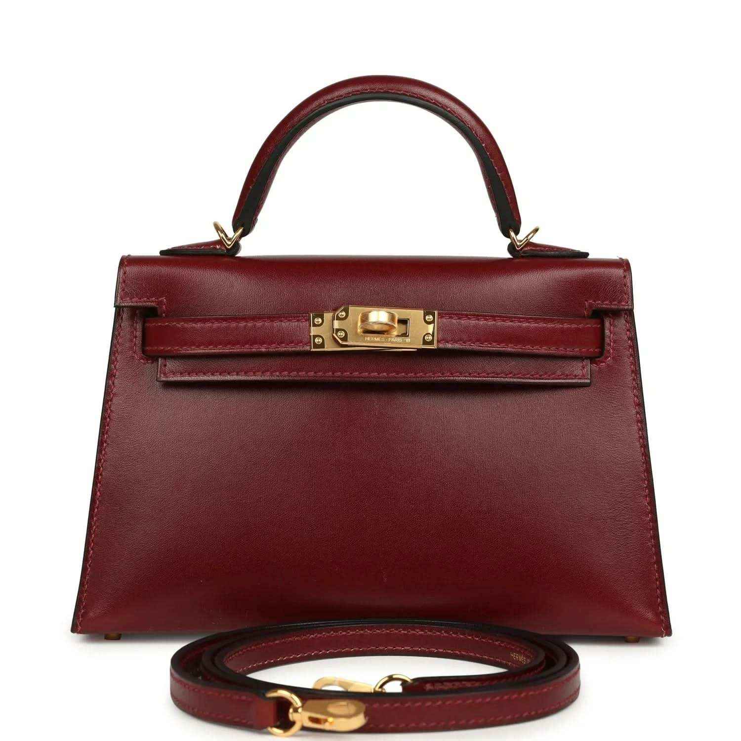Red leather handbag with top handle, gold front lock, and matching shoulder strap.