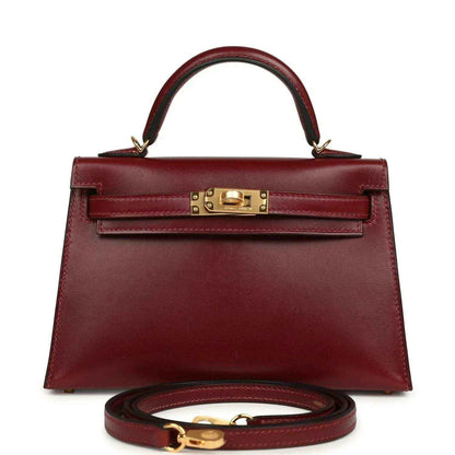 Red leather handbag with top handle, gold front lock, and matching shoulder strap.