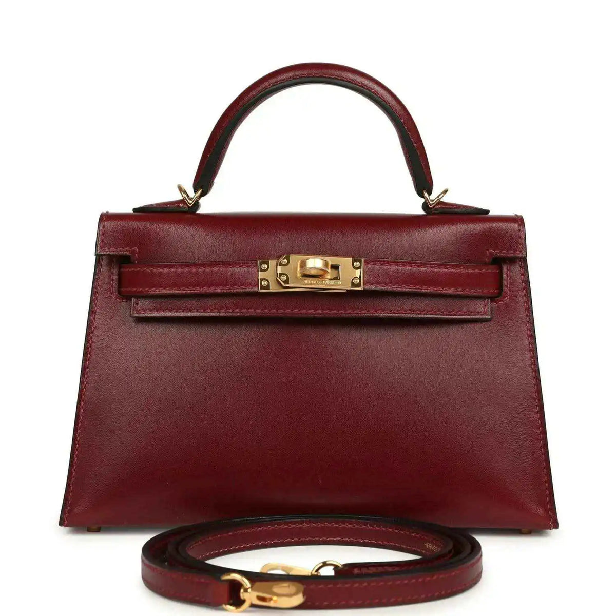Red leather handbag with top handle, gold front lock, and matching shoulder strap.