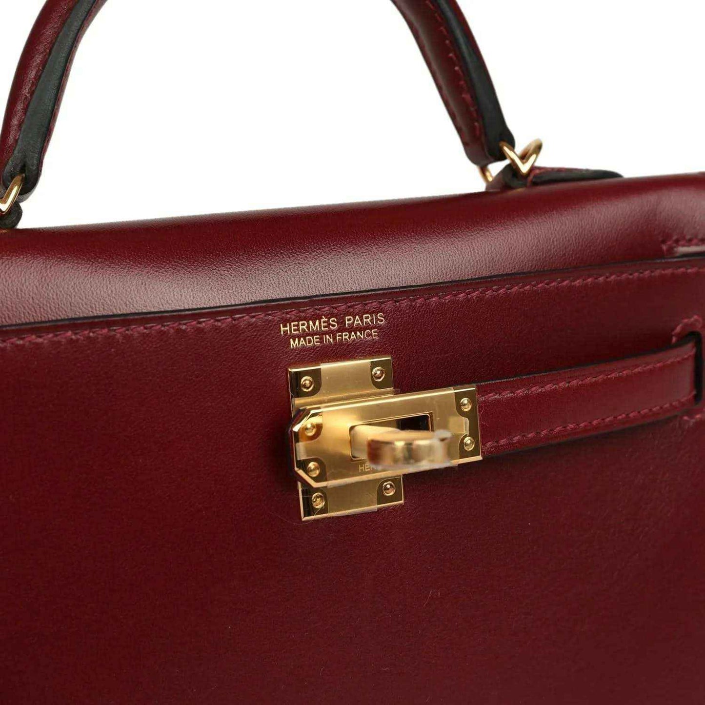 Red leather handbag close-up with Hermès Paris stamp and gold lock hardware.