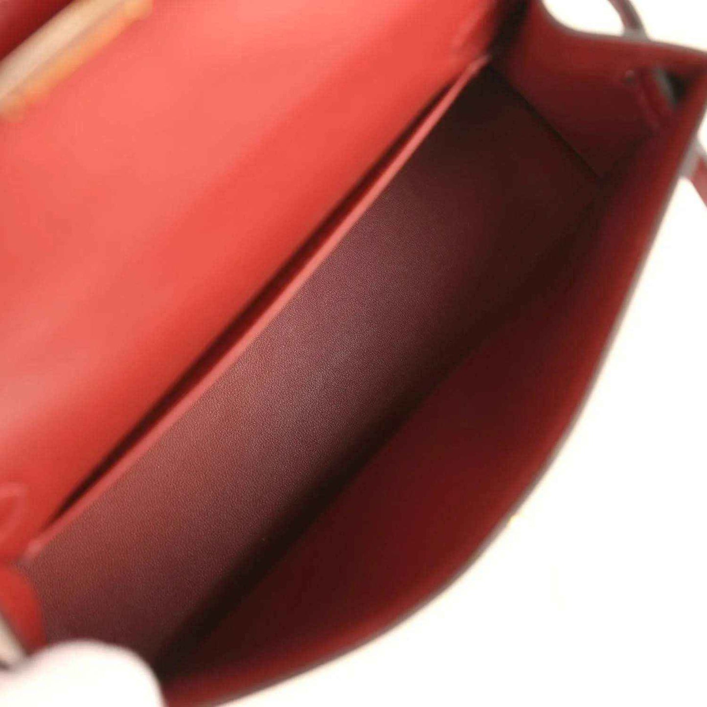 Red leather handbag interior close-up with smooth lining and folded edge.