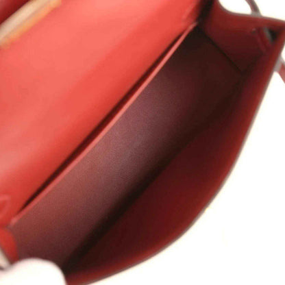 Red leather handbag interior close-up with smooth lining and folded edge.