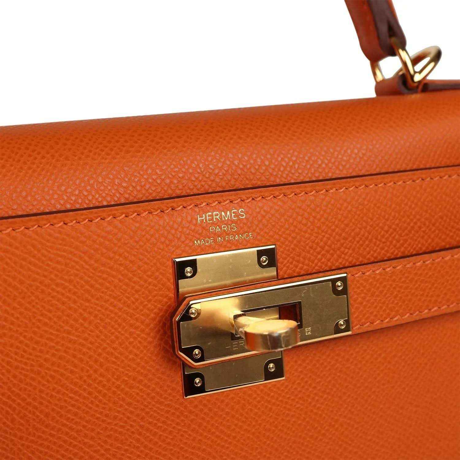Orange leather Kelly bag with Hermes stamp and gold turn-lock hardware close-up.
