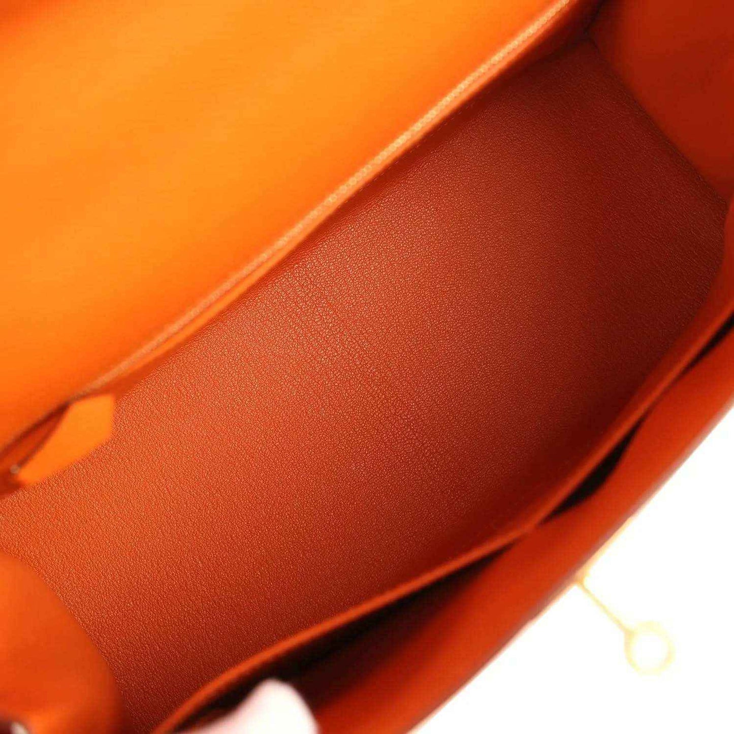 Orange leather Kelly bag interior with textured surface, close-up.