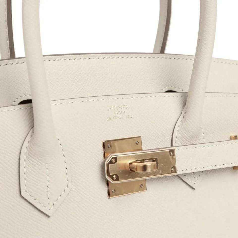Light cream leather handbag front with gold turn-lock clasp and stitched seams