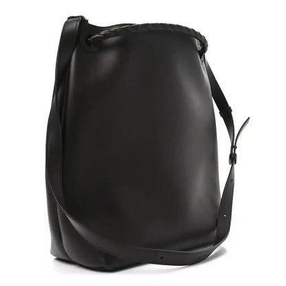 Small bucket bag in dark leather with structured curved shape and shoulder strap