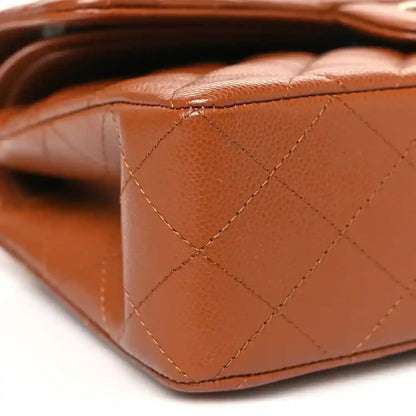 Caramel quilted leather side panel of a small double flap bag with visible stitching