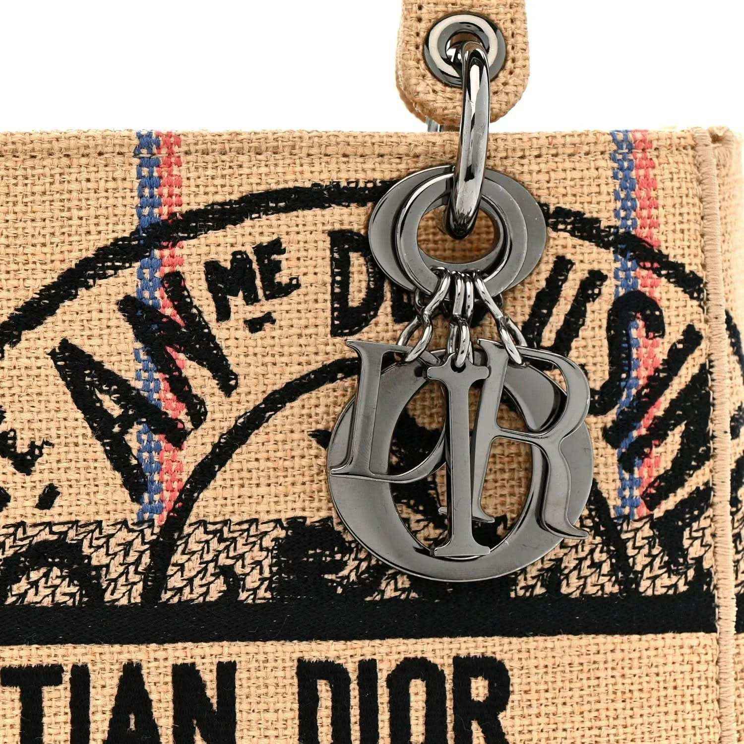 Beige tote bag front close-up with metal key clasp and black logo graphic