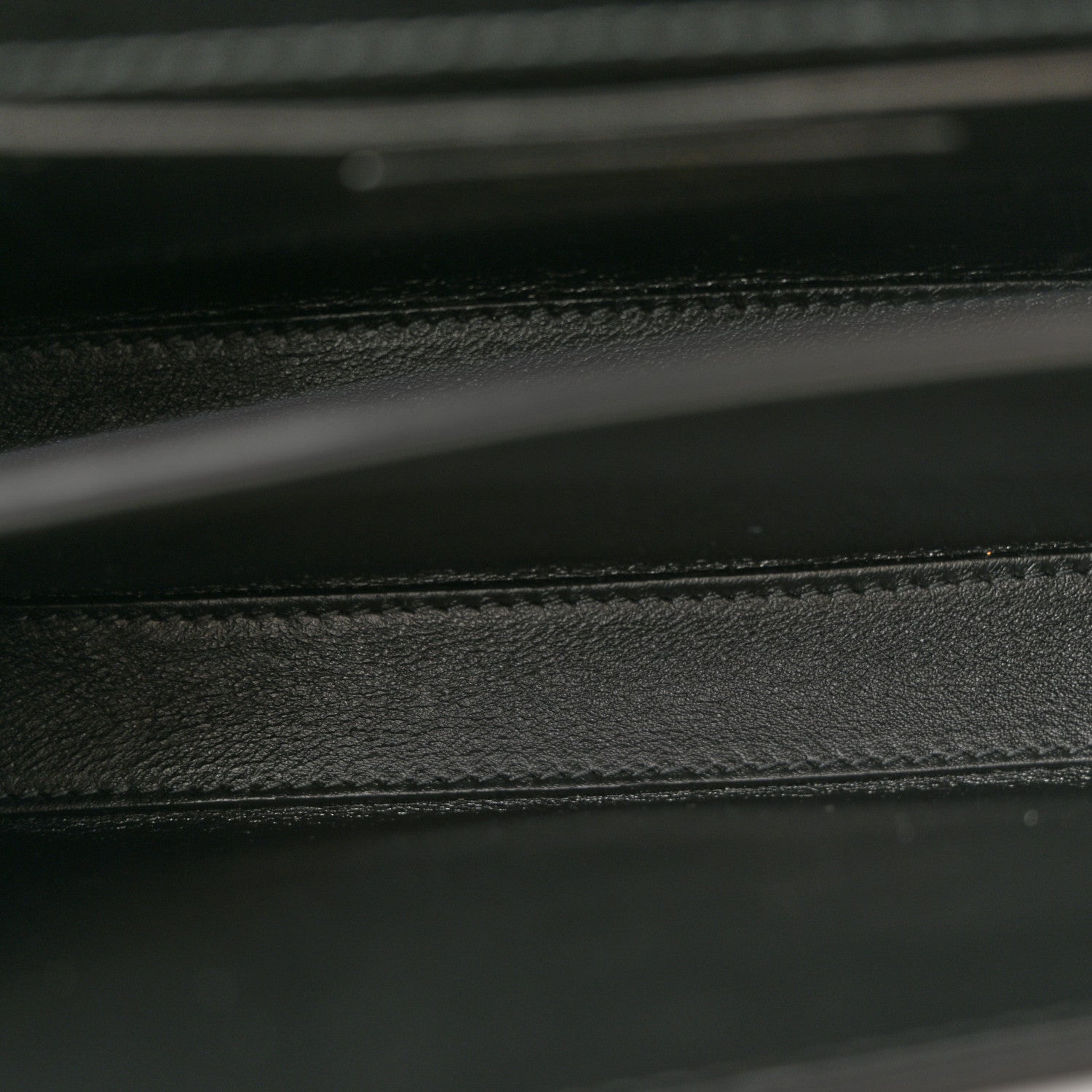Black leather bag interior seam and textured lining detail.
