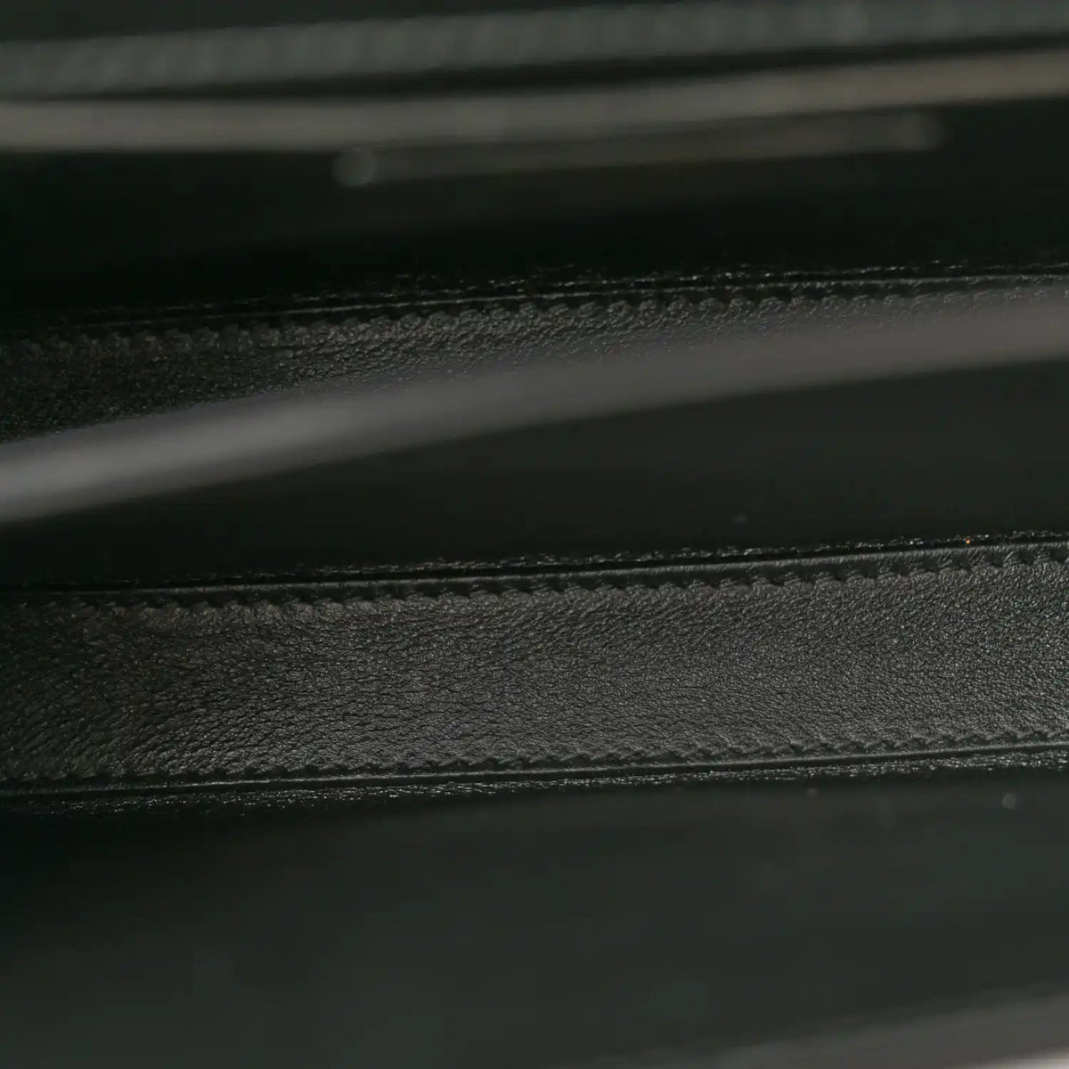 Black leather bag interior seam and textured lining detail.