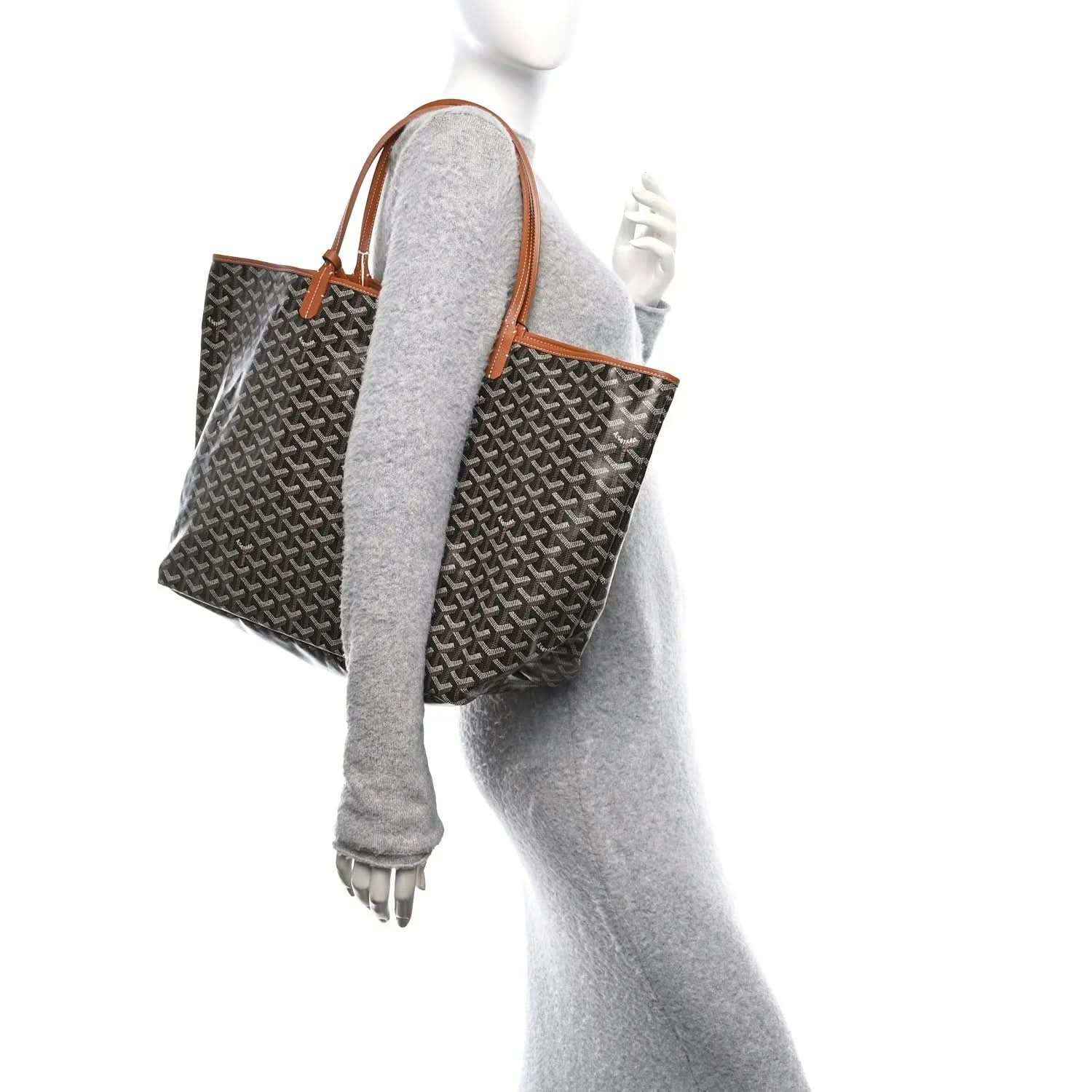 Black monogram tote bag with tan leather handles, shown from side