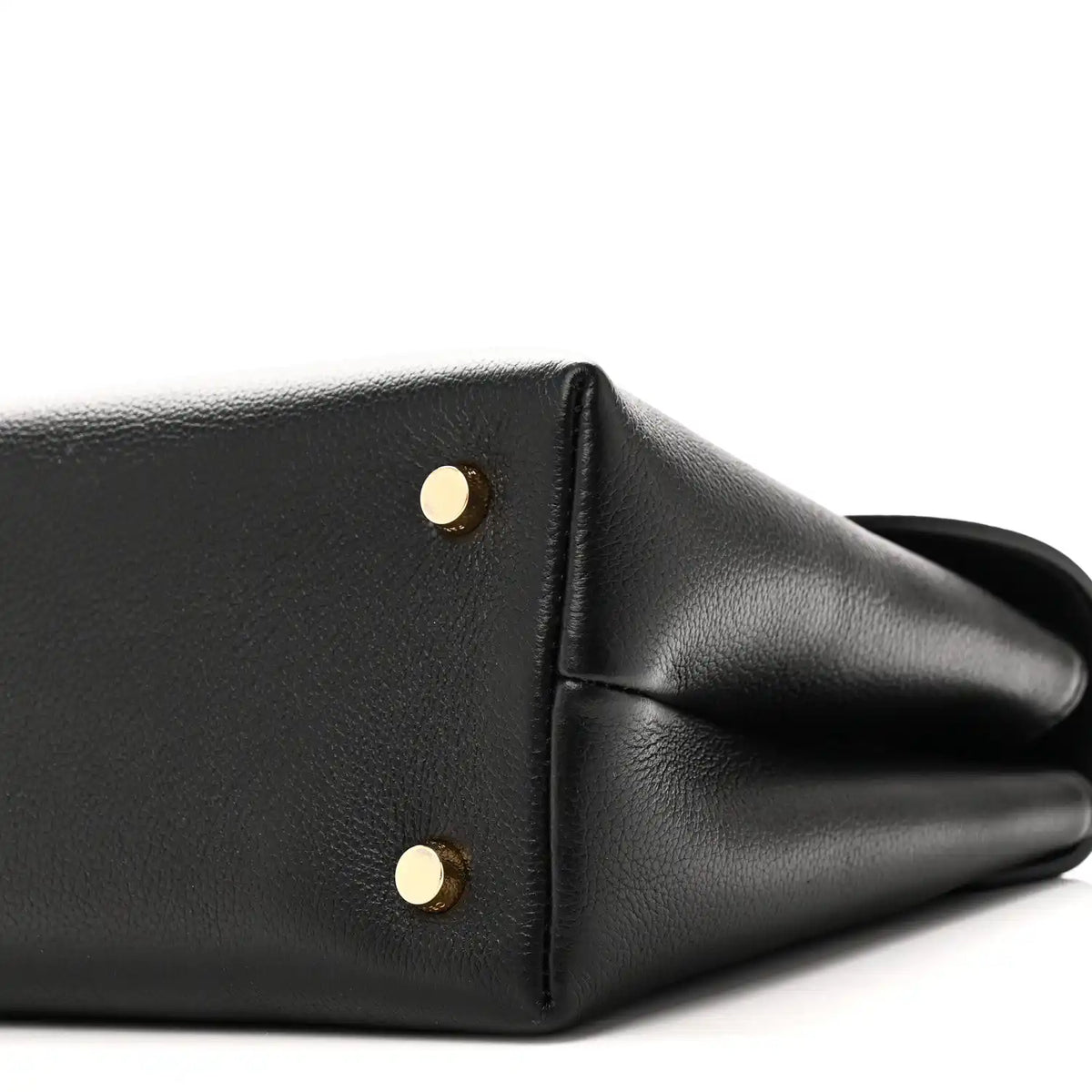 Black leather handbag corner with two gold studs and curved side panel