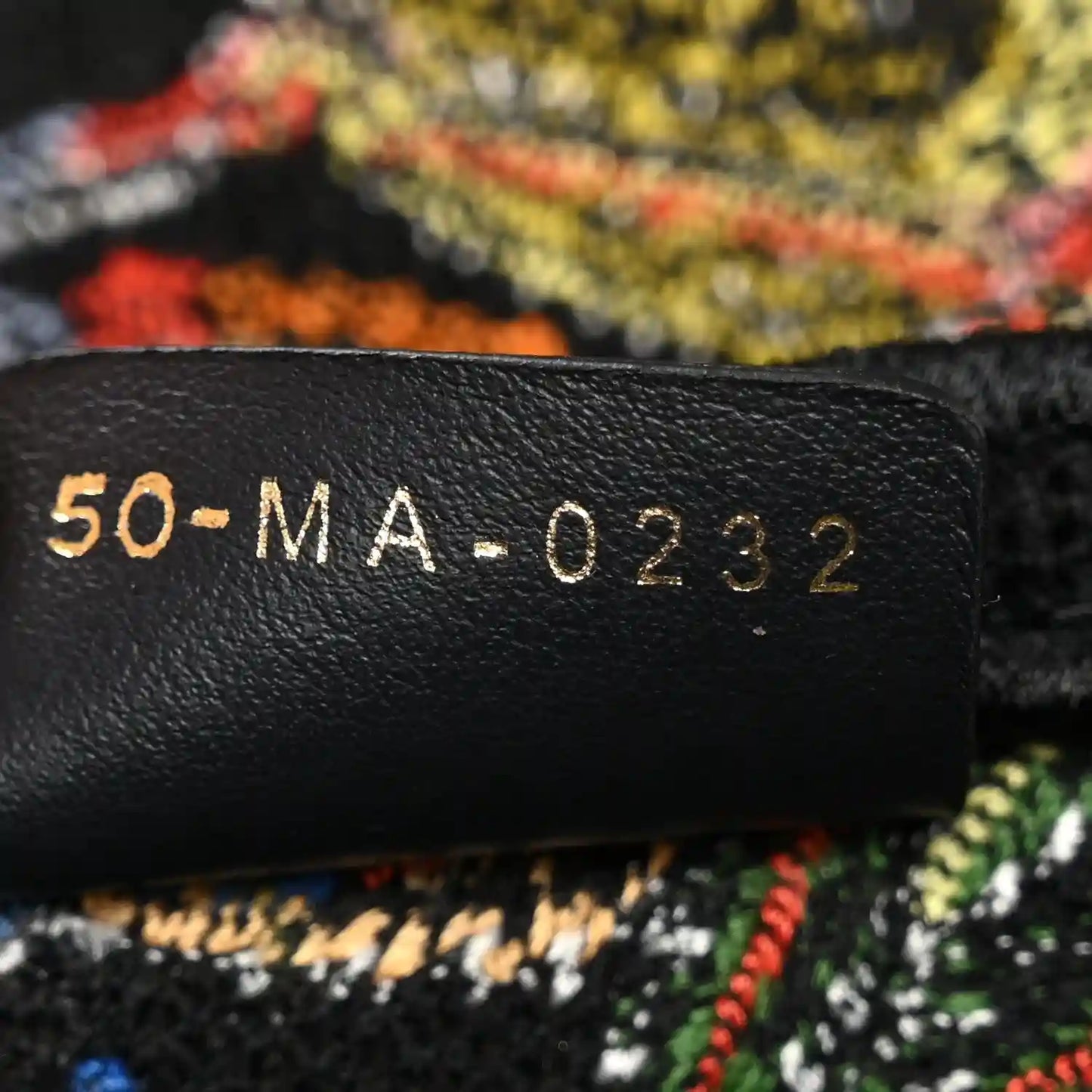 Black leather label with '50-MA-0232' code on embroidered bag interior