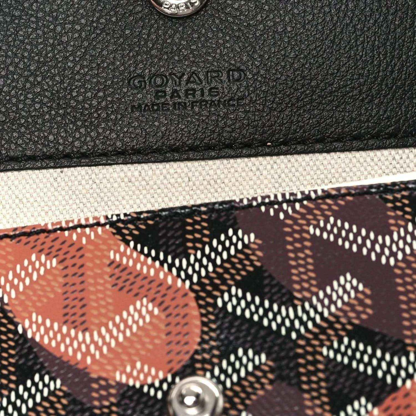 PM tote bag detail: textured black leather panel with embossed logo and a multicolor printed canvas