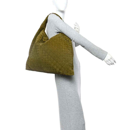 Olive suede intrecciato hobo bag held beside a model’s arm