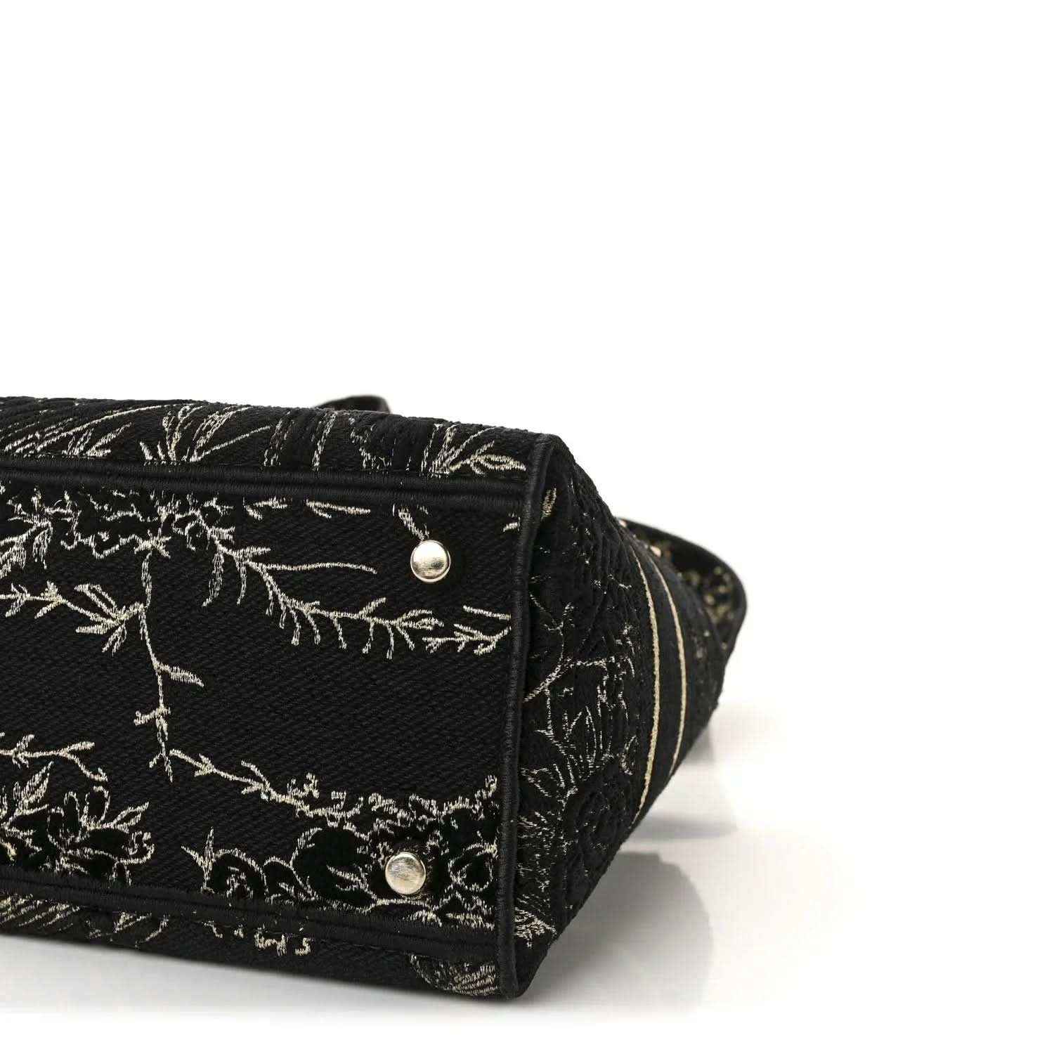 Close-up of black embroidered handbag bottom with gold button hardware