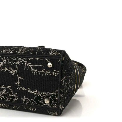 Close-up of black embroidered handbag bottom with gold button hardware