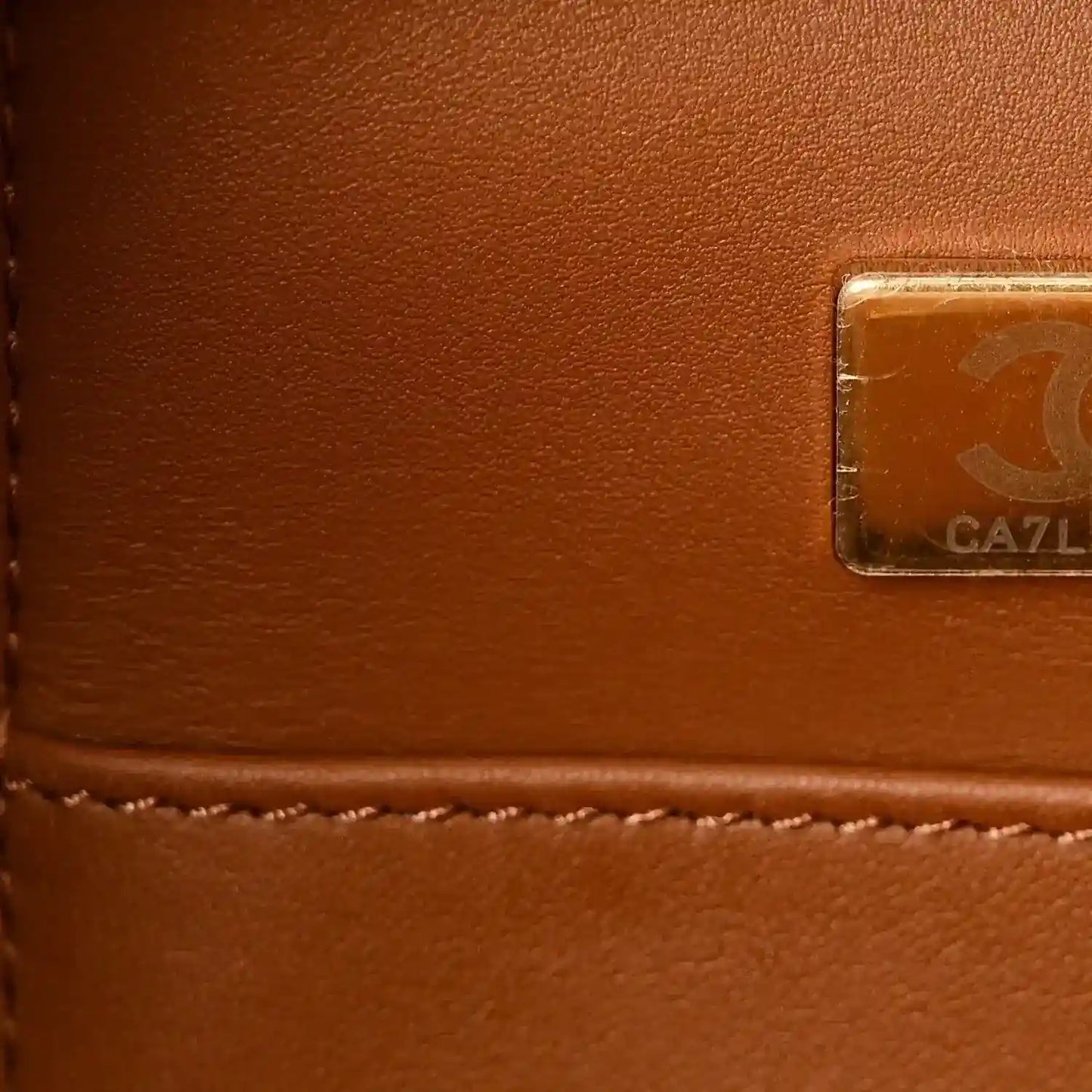 Leather tote tag with embossed emblem on brown lambskin