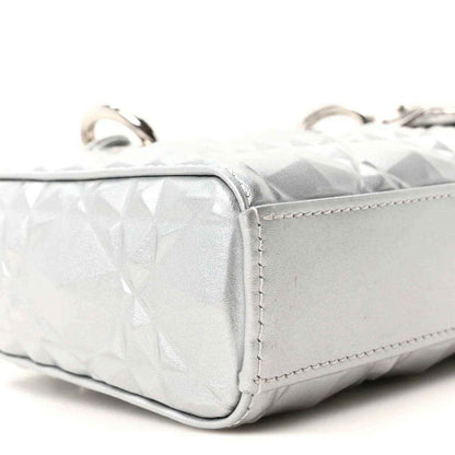 Small metallic silver handbag side panel with geometric texture and stitched edge.