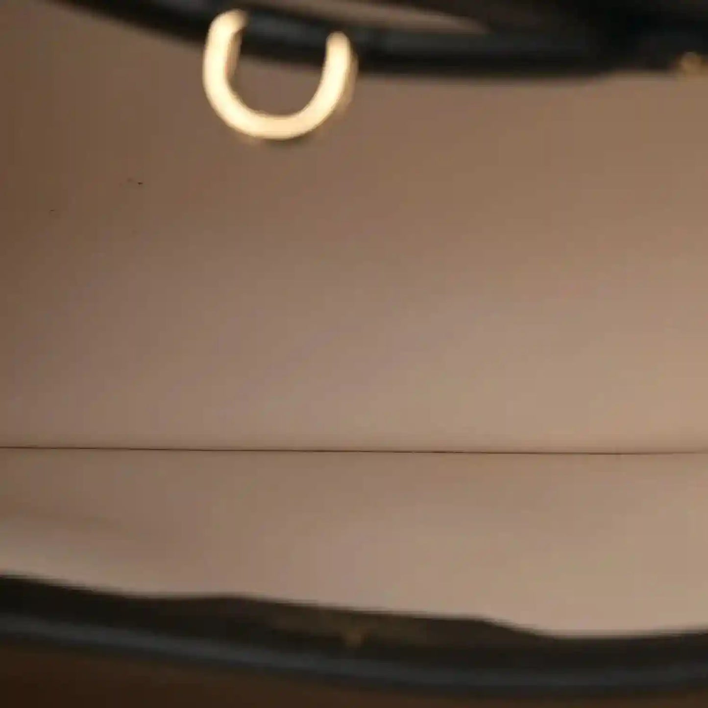 Close-up of gold-toned ring on black leather bag strap