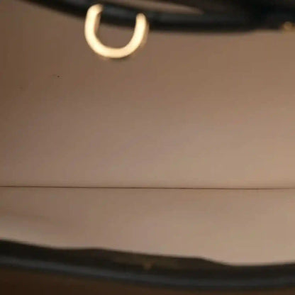 Close-up of gold-toned ring on black leather bag strap
