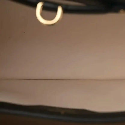 Close-up of gold-toned ring on black leather bag strap