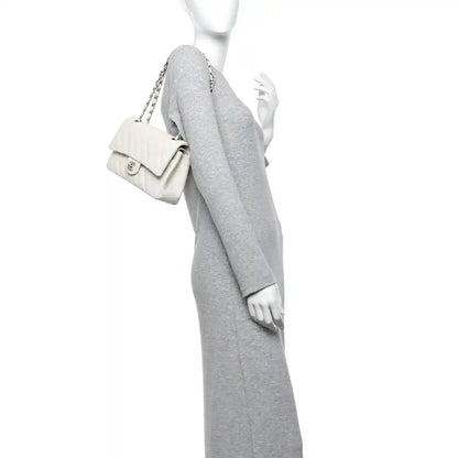 White quilted double flap bag with chain strap held by mannequin