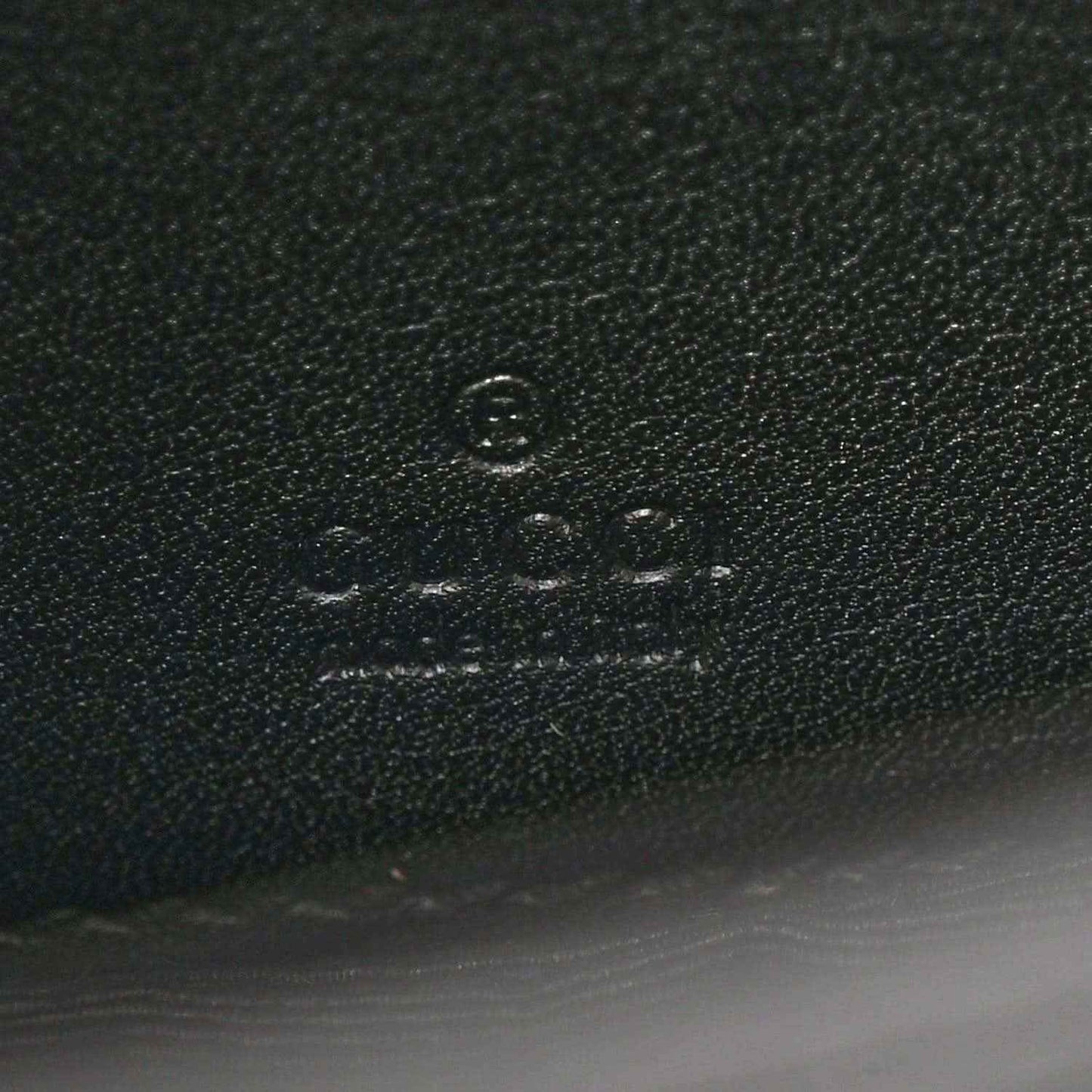 Close-up of embossed mark on black textured mini bag material