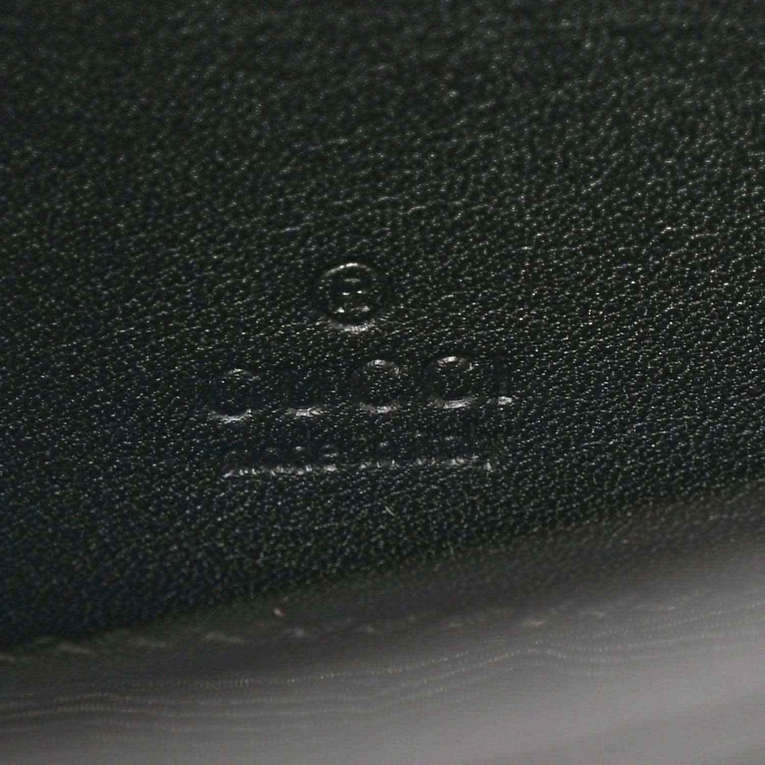 Close-up of embossed mark on black textured mini bag material